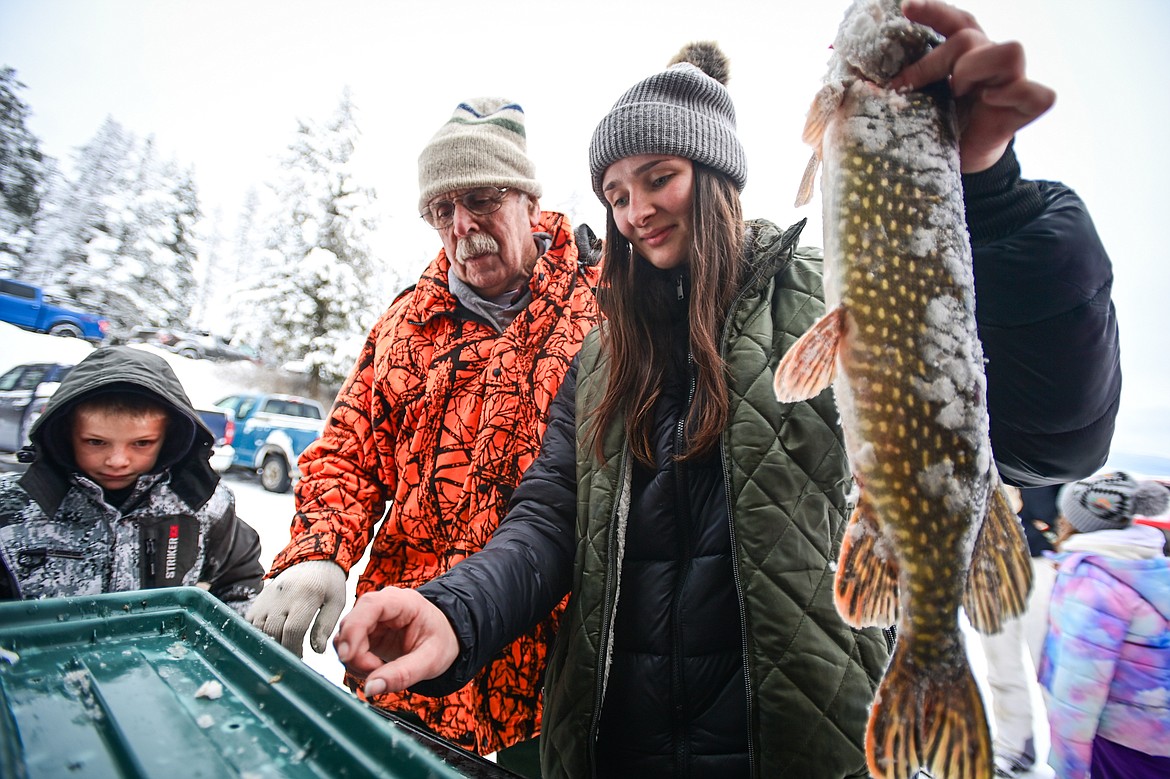 Serena Keil-Hoye and Warren Illi place a northern pike on the scale caught by Garin Hicks, left, at the 53rd annual Sunriser Lions Ice Fishing Derby on Smith Lake in Kila on Saturday, Jan. 4. (Casey Kreider/Daily Inter Lake)