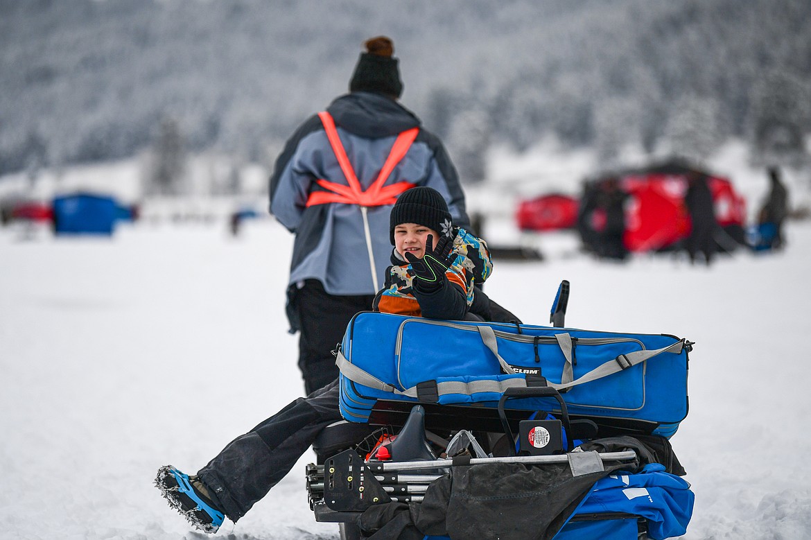 Callen Tyrone waves as his mom Amber pulls their sled full of ice fishing gear out onto Smith Lake at the 53rd annual Sunriser Lions Ice Fishing Derby in Kila on Saturday, Jan. 4. (Casey Kreider/Daily Inter Lake)