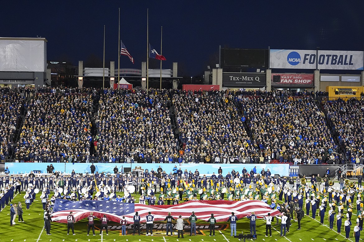 A United States and a Texas flag are seen at half mast in honor of former President Jimmy Carter as a large flag is unfurled at midfield at Toyota Stadium during the national anthem ahead of the FCS Championship NCAA college football game between Montana State and North Dakota State, Monday, Jan. 6, 2025, in Frisco, Texas. (AP Photo/Julio Cortez)