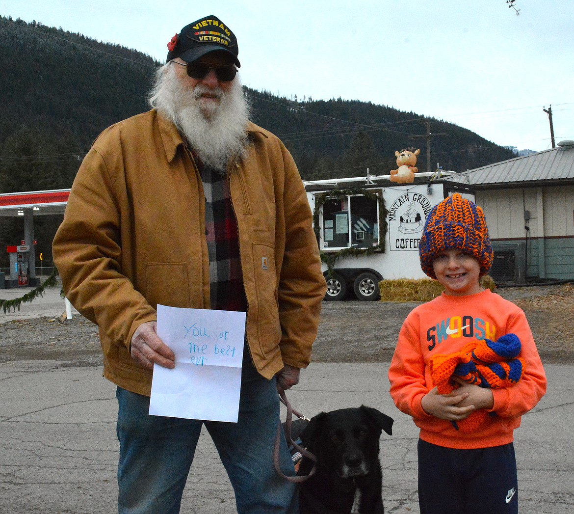 Ed Holterman, left, met MJ Allard, along with his Mom on January 2, to present him with a arm full of orange and blue knitted winter hats. The young boy had requested the special color combination on Halloween over two months back, and Holterman made it his mission to find the boy again and grant him his wish. (Mineral Independent/Amy Quinlivan)