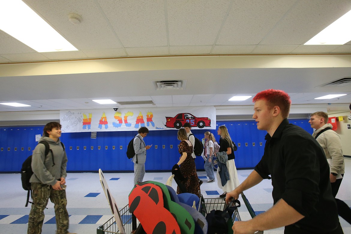 Coeur d'Alene High School Student Body President Payton Conn rolls past a NASCAR poster Tuesday after Fight for the Fish cheer practice.