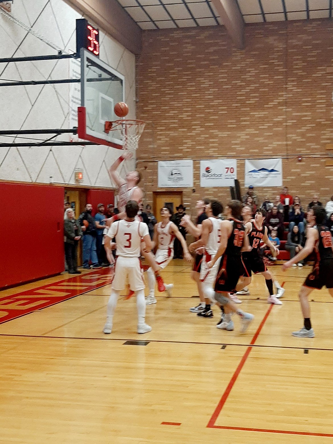 Noxon players (white uniforms) swarm to the basket as senior Shane Murray puts up a shot against Plains this past Friday in Noxon. (Photo by Jenna Kayser)