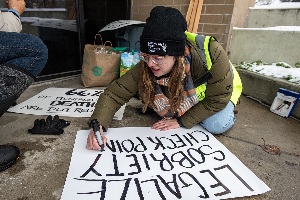 Carli Seymour with the Montana Bar Fairies works to make picketing signs in front of Flathead County Justice Center on Wednesday, Jan. 8. (Avery Howe/Bigfork Eagle)