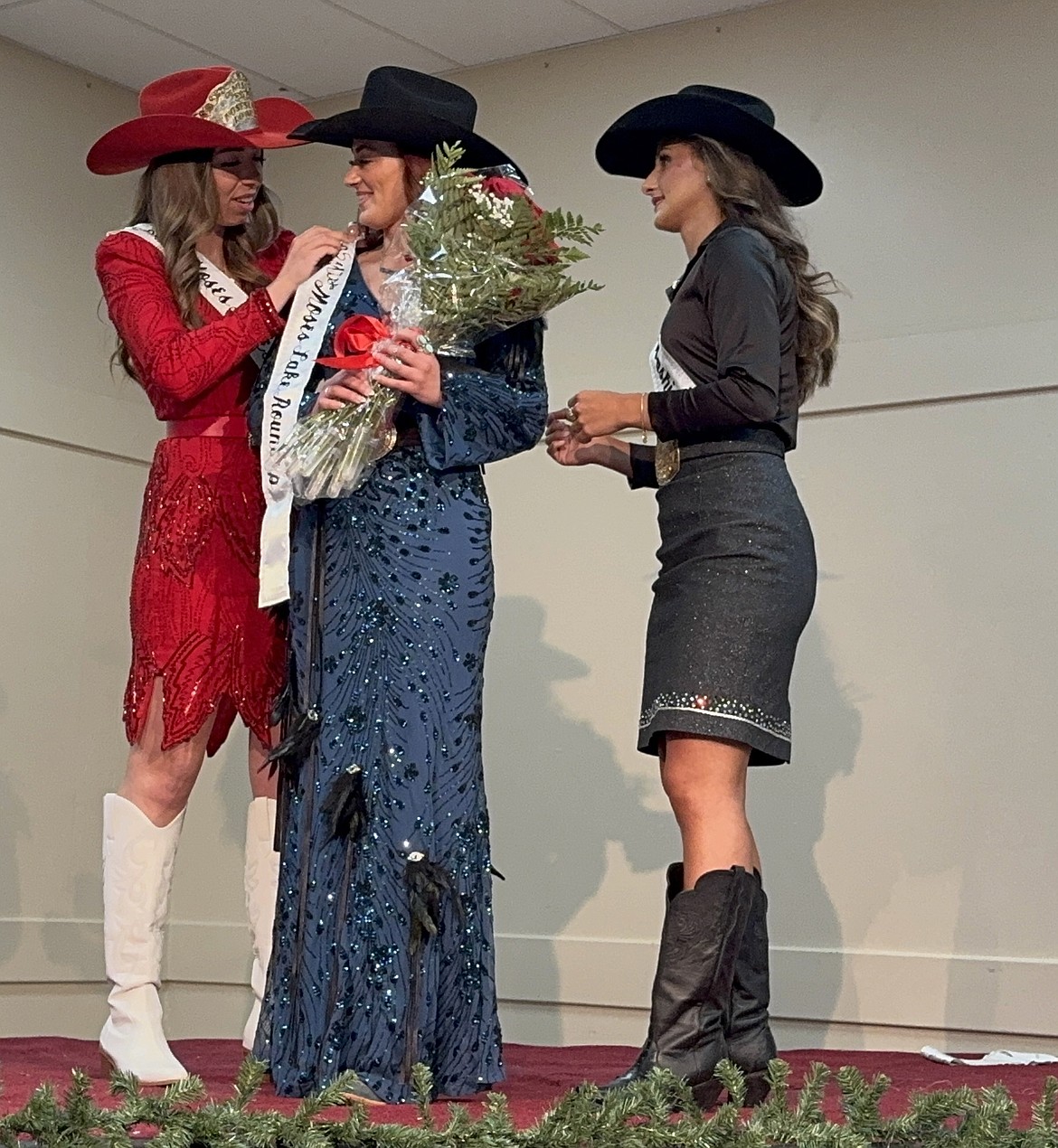Kaylee Stump, 20, of Ephrata, receives the sash honoring her as Miss Moses Lake Roundup 2025 from outgoing Moses Lake Roundup Queen Alexis Shoults, while Miss Rodeo Washington 2024, Piper Schirm, looks on.