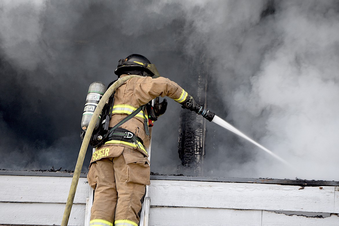 Libby Volunteer Fire Department's Steve Scheer sprays water at the scene of an apartment fire Tuesday afternoon on Main Avenue in Libby. (Scott Shindledecker/The Western News)