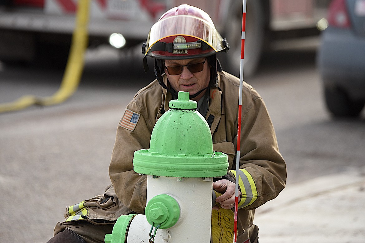 Libby Volunteer Fire Department Chief Steve Lauer attaches a hose to a hydrant at the scene of an apartment fire Tuesday afternoon on Main Avenue in Libby. (Scott Shindledecker/The Western News)