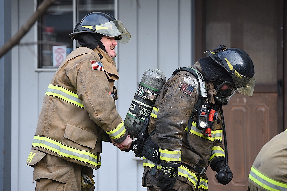 Libby Volunteer Fire Department crew members get fresh oxygen tanks at the scene of an apartment fire Tuesday afternoon on Main Avenue in Libby. (Scott Shindledecker/The Western News)