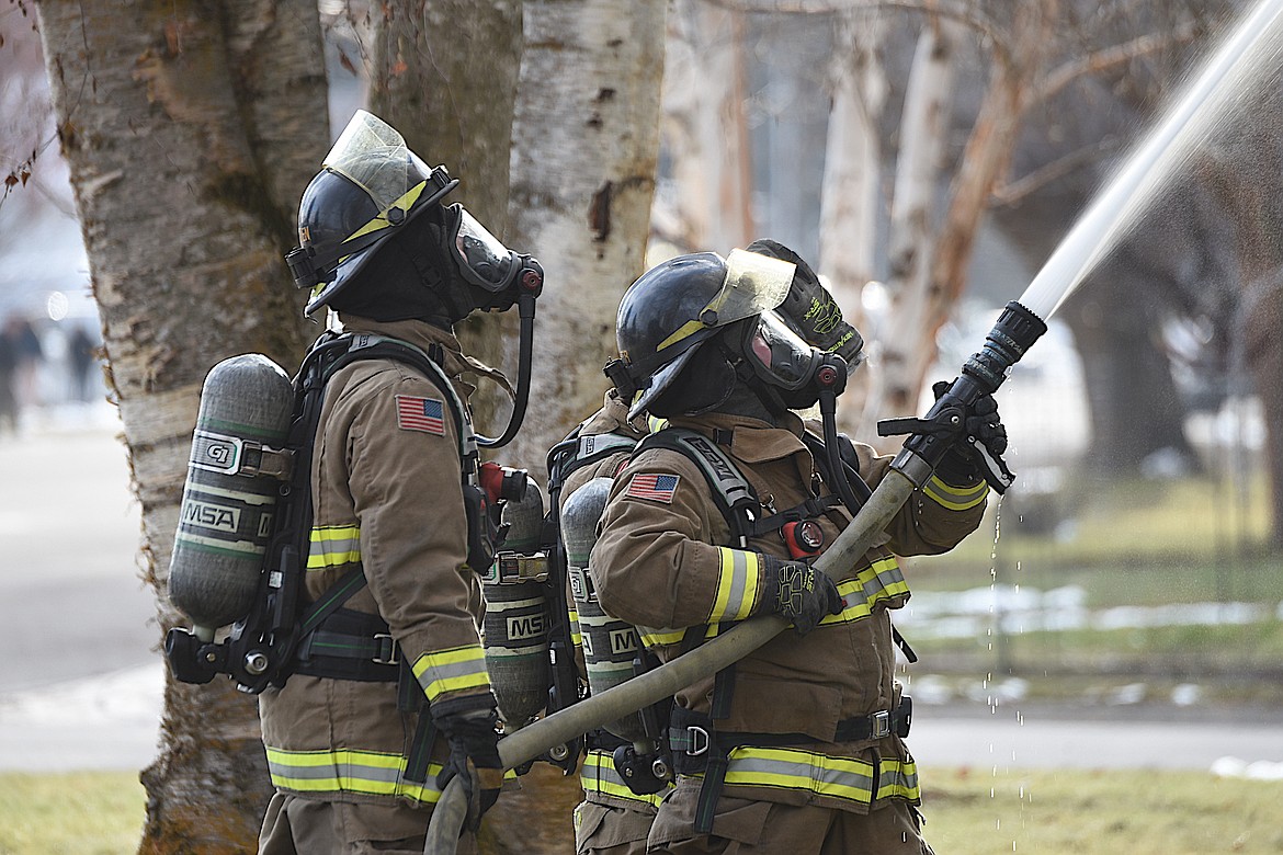 Libby Volunteer Fire Department firefighters train a hose on flames at the scene of an apartment fire Tuesday afternoon on Main Avenue in Libby. (Scott Shindledecker/The Western News)