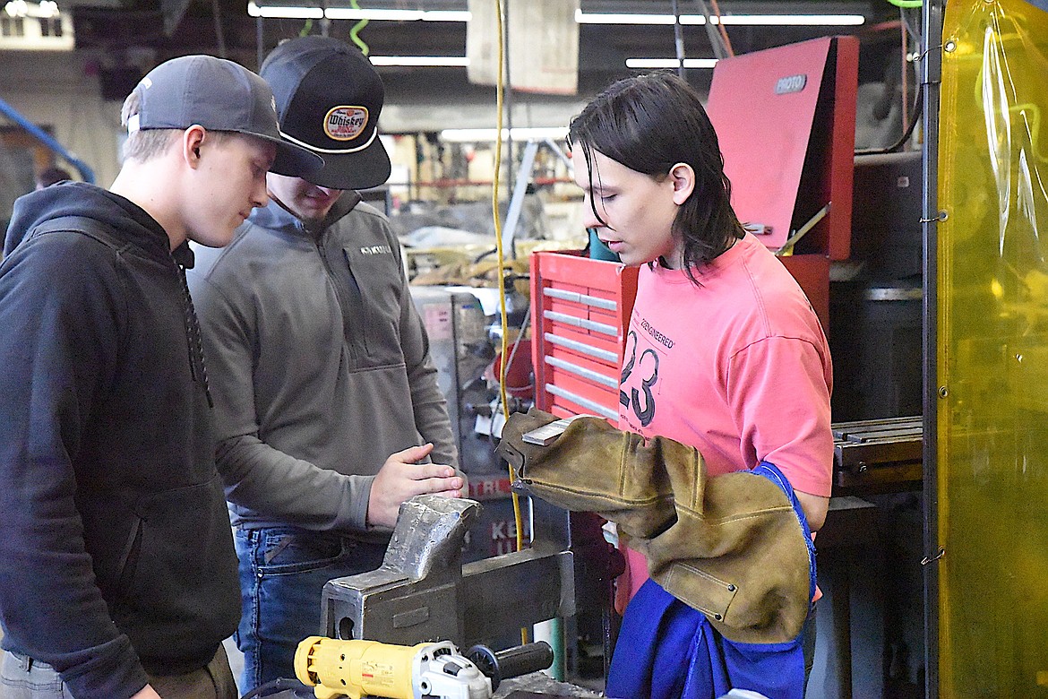 Libby High School junior Dominic Thom holds a welded piece of medal as classmates Ian Thom and Parker Bache observe. (Scott Shindledecker/The Western News)