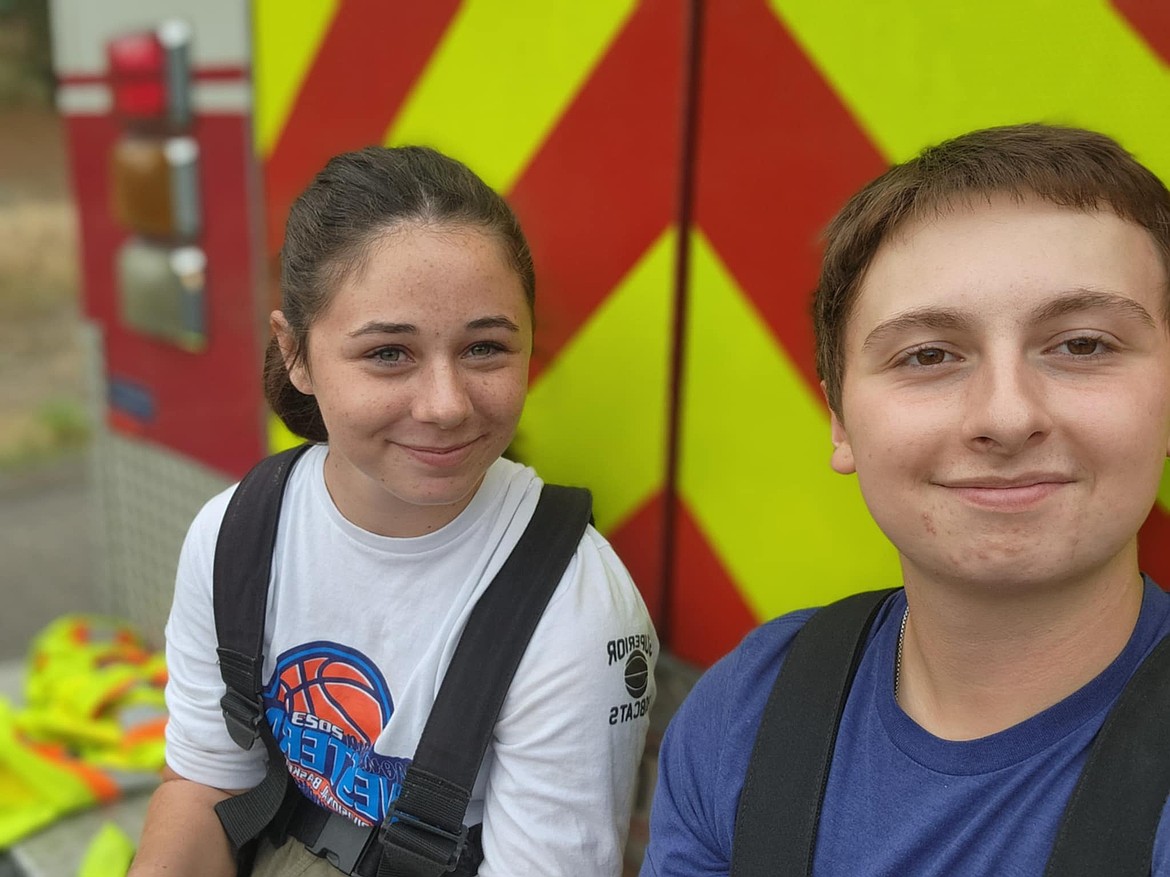 Junior Firefighter Program director Anthony Dodd, right, sits on the back of one of the Superior Volunteer Fire Department trucks with junior volunteer Cami Quick. (Photo courtesy/Anthony Dodd)