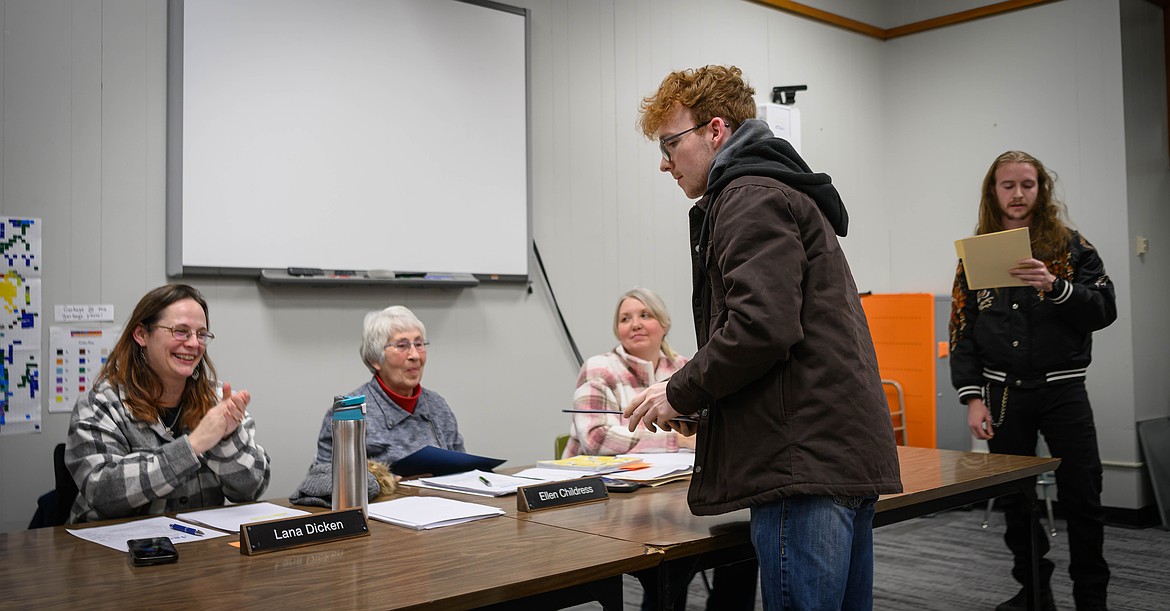 Plains High School seniors Logan Steinebach and Django Oakcedar hand out awards to Plains School Board members. (Tracy Scott/Valley Press)