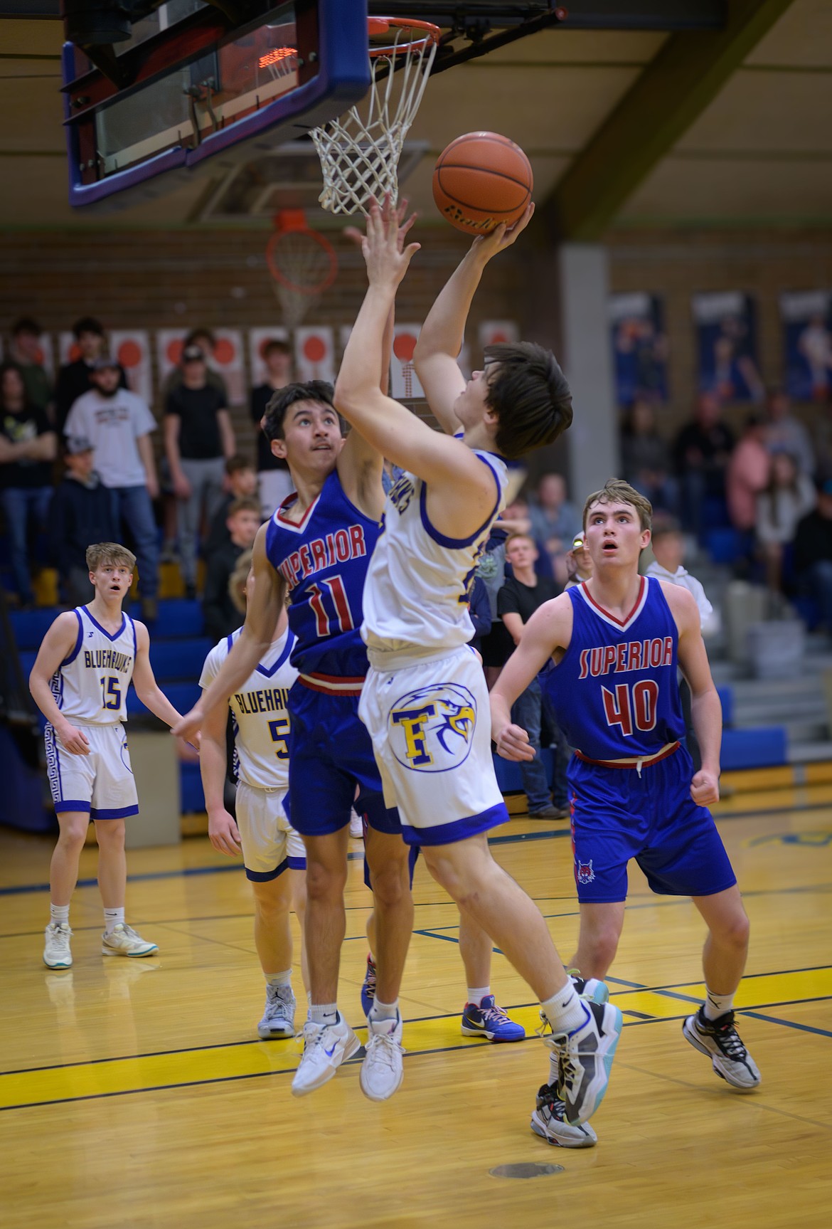 Thompson Falls forward Jacob Howell (white) goes up for a shot over Superior's Trizten Avila (11) during their game Saturday night in Thompson Falls. (Tracy Scott/Valley Press)