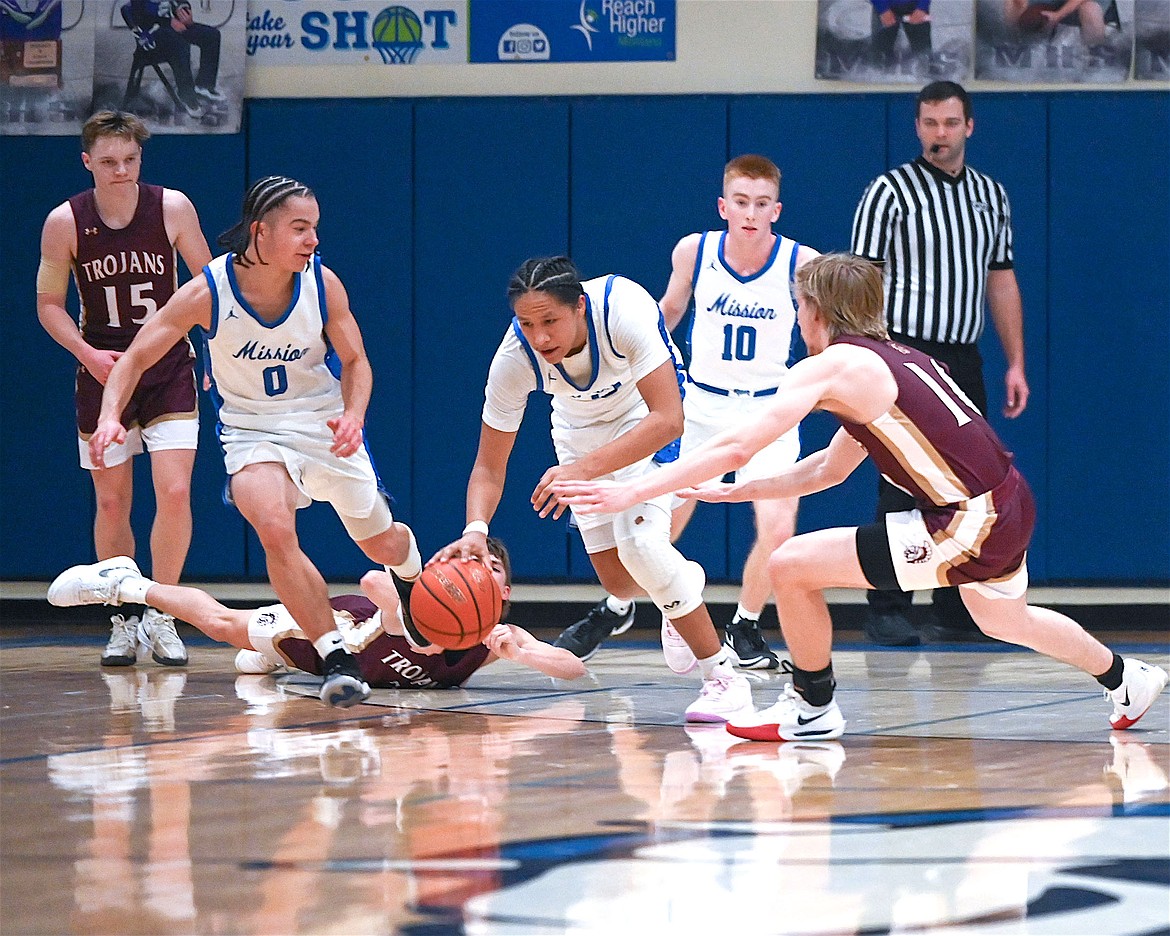 Bulldogs Lex LaFrombois, Vincent Shepard and Harlon Leishman swipe the ball from the Trojans during a close contest last week. (Christa Umphrey photo)