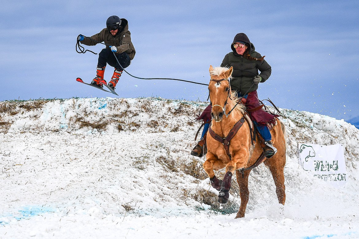 A horseback rider pulls a skier over a jump at Whitefish Skijoring on West Springcreek Road on Saturday, Feb. 22. (Casey Kreider/Daily Inter Lake)