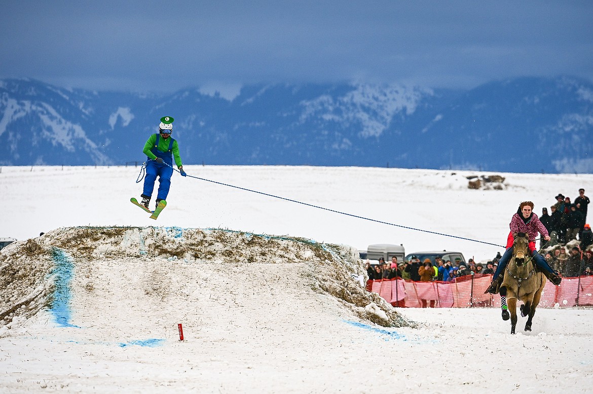 A horseback rider pulls a skier over a jump at Whitefish Skijoring on West Springcreek Road on Saturday, Feb. 22. (Casey Kreider/Daily Inter Lake)