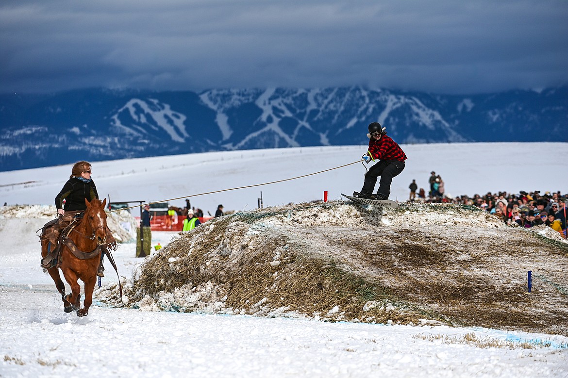 A horseback rider pulls a snowboarder over a jump at Whitefish Skijoring on West Springcreek Road on Saturday, Feb. 22. (Casey Kreider/Daily Inter Lake)
