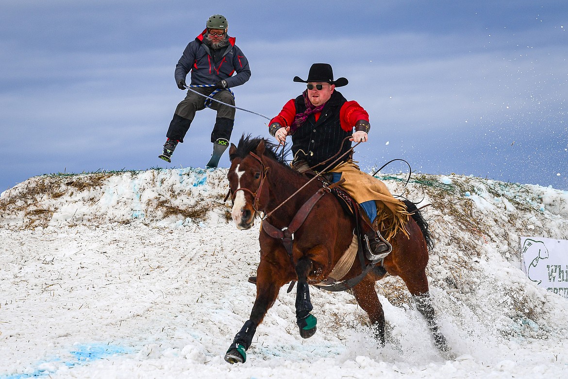 A horseback rider pulls a skier over a jump at Whitefish Skijoring on West Springcreek Road on Saturday, Feb. 22. (Casey Kreider/Daily Inter Lake)