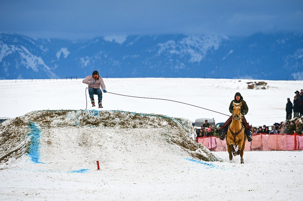 A horseback rider pulls a skier over a jump at Whitefish Skijoring on West Springcreek Road on Saturday, Feb. 22. (Casey Kreider/Daily Inter Lake)