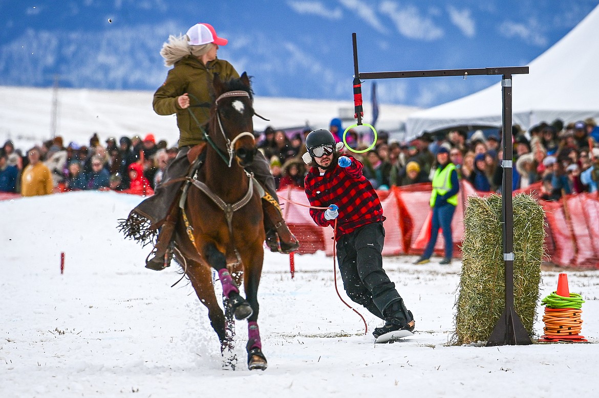 A snowboarder secures a ring as he's pulled through the course at Whitefish Skijoring on West Springcreek Road on Saturday, Feb. 22. (Casey Kreider/Daily Inter Lake)