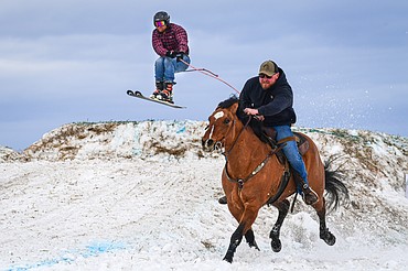 A horseback rider pulls a skier over a jump at Whitefish Skijoring on West Springcreek Road on Saturday, Feb. 22. (Casey Kreider/Daily Inter Lake)
