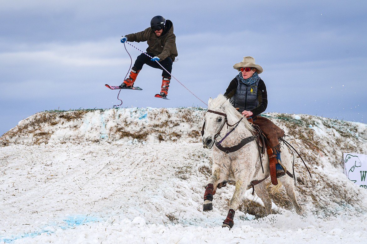 A horseback rider pulls a skier over a jump at Whitefish Skijoring on West Springcreek Road on Saturday, Feb. 22. (Casey Kreider/Daily Inter Lake)