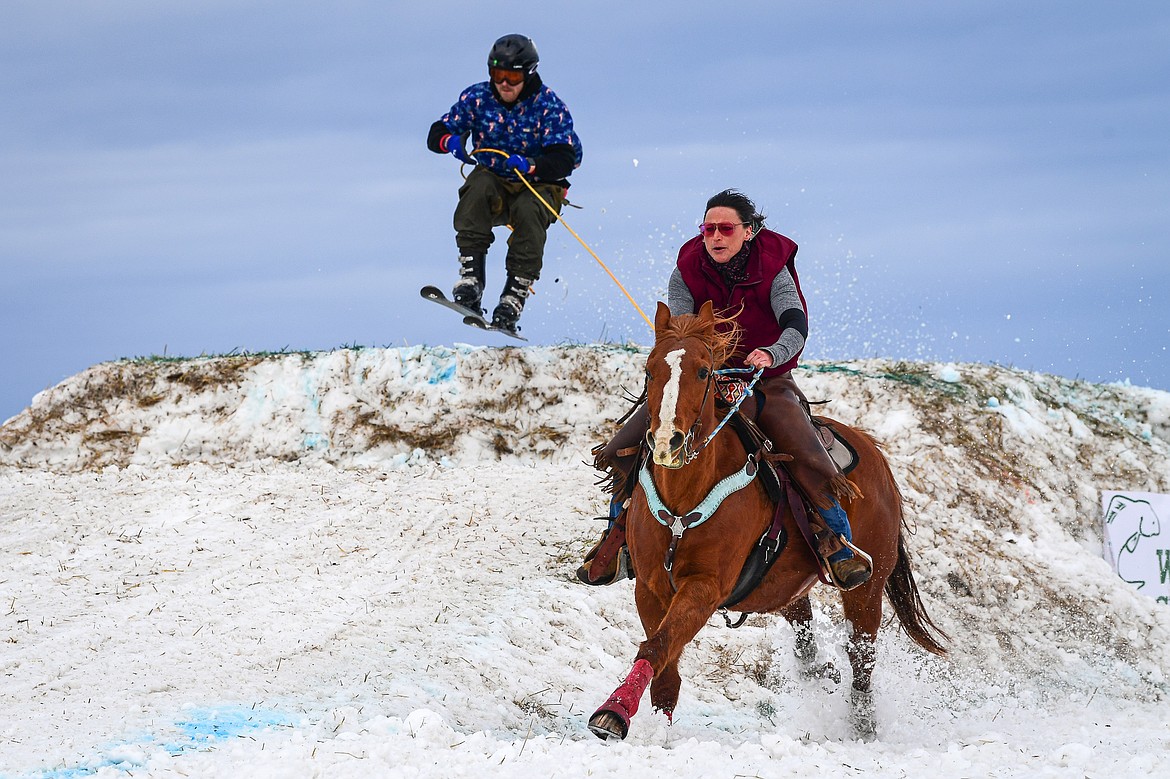 A horseback rider pulls a skier over a jump at Whitefish Skijoring on West Springcreek Road on Saturday, Feb. 22. (Casey Kreider/Daily Inter Lake)