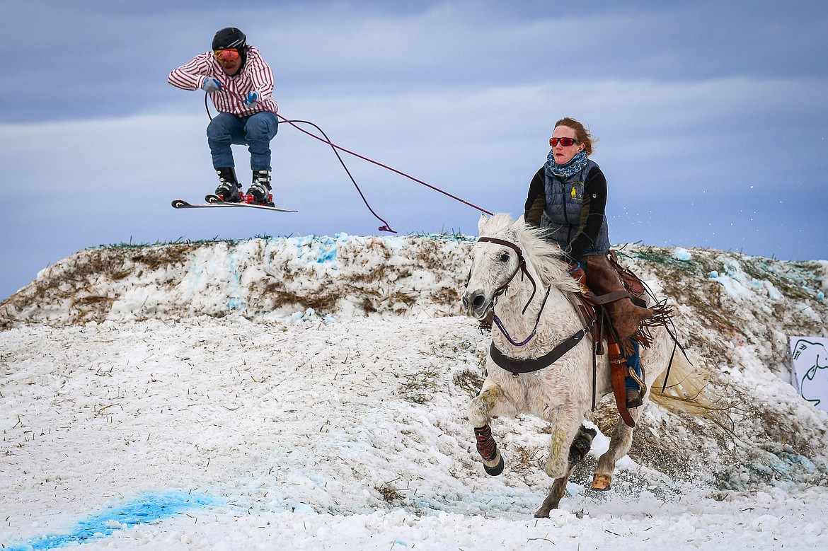 A horseback rider pulls a skier over a jump at Whitefish Skijoring on West Springcreek Road on Saturday, Feb. 22. (Casey Kreider/Daily Inter Lake)