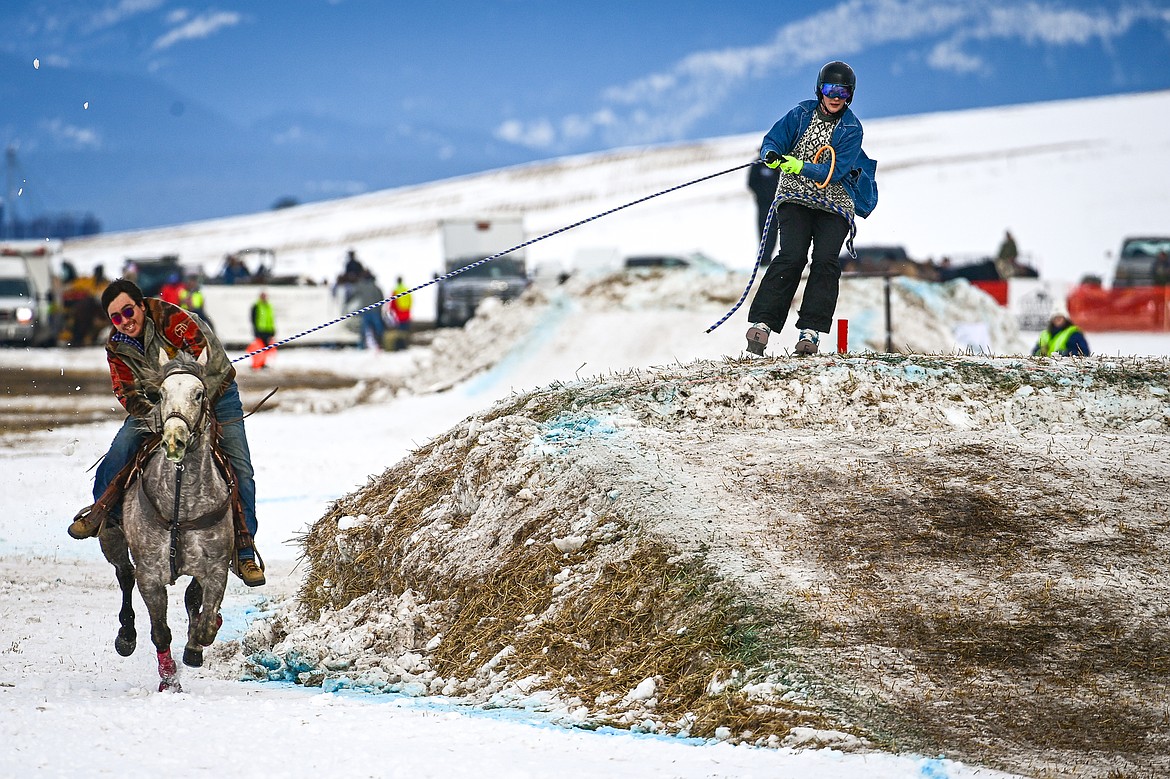 A horseback rider pulls a skier over a jump at Whitefish Skijoring on West Springcreek Road on Saturday, Feb. 22. (Casey Kreider/Daily Inter Lake)