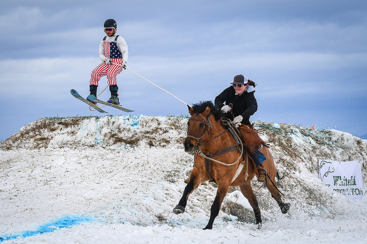 A horseback rider pulls a skier over a jump at Whitefish Skijoring on West Springcreek Road on Saturday, Feb. 22. (Casey Kreider/Daily Inter Lake)