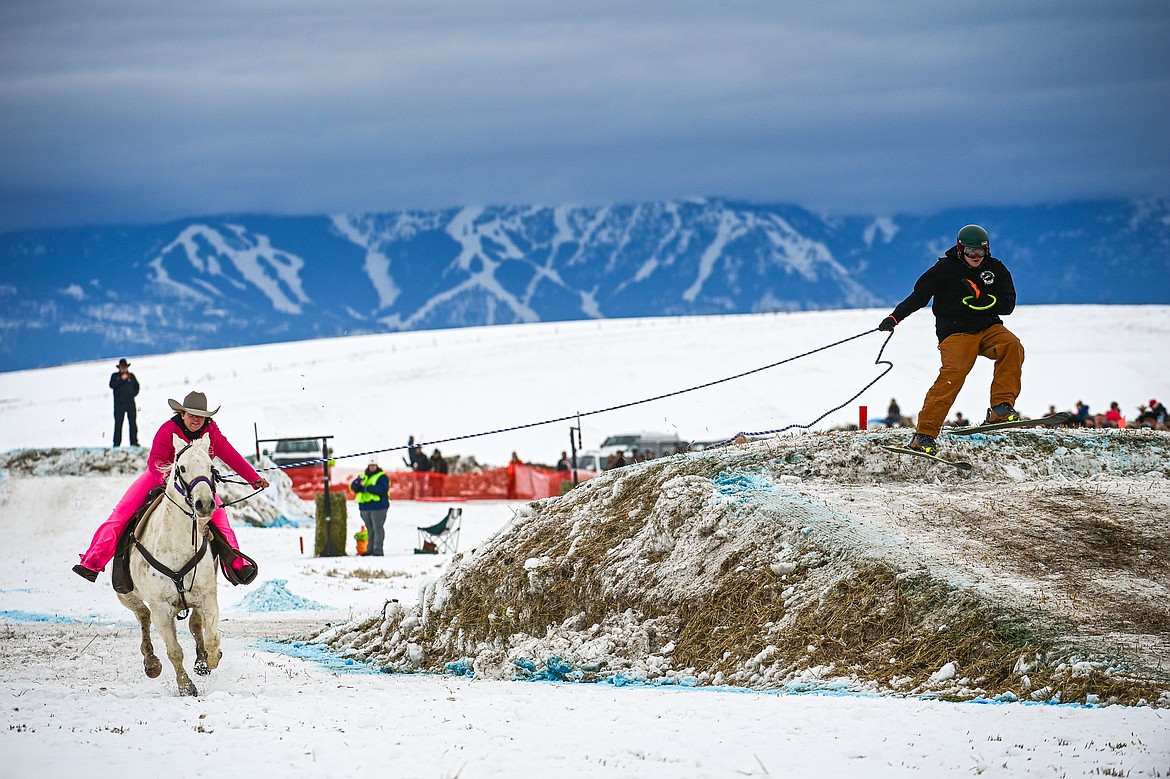 A horseback rider pulls a skier over a jump at Whitefish Skijoring on West Springcreek Road on Saturday, Feb. 22. (Casey Kreider/Daily Inter Lake)