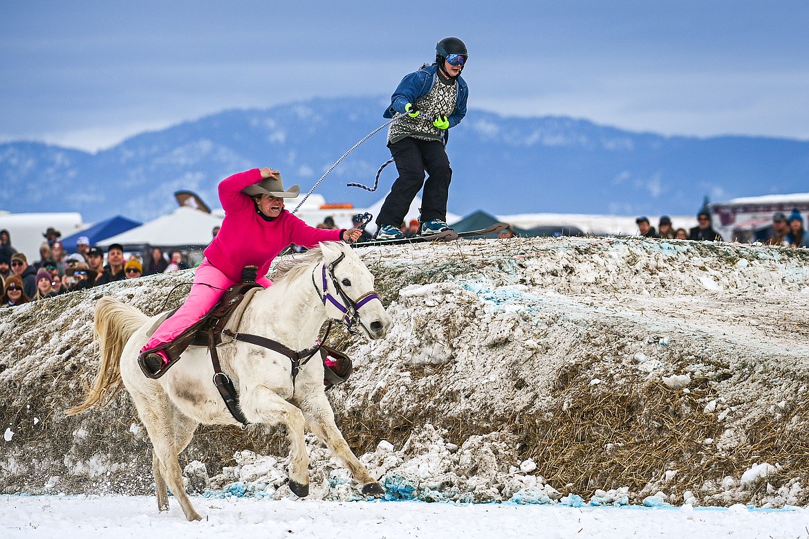A horseback rider pulls a snowboarder over a jump at Whitefish Skijoring on West Springcreek Road on Saturday, Feb. 22. (Casey Kreider/Daily Inter Lake)