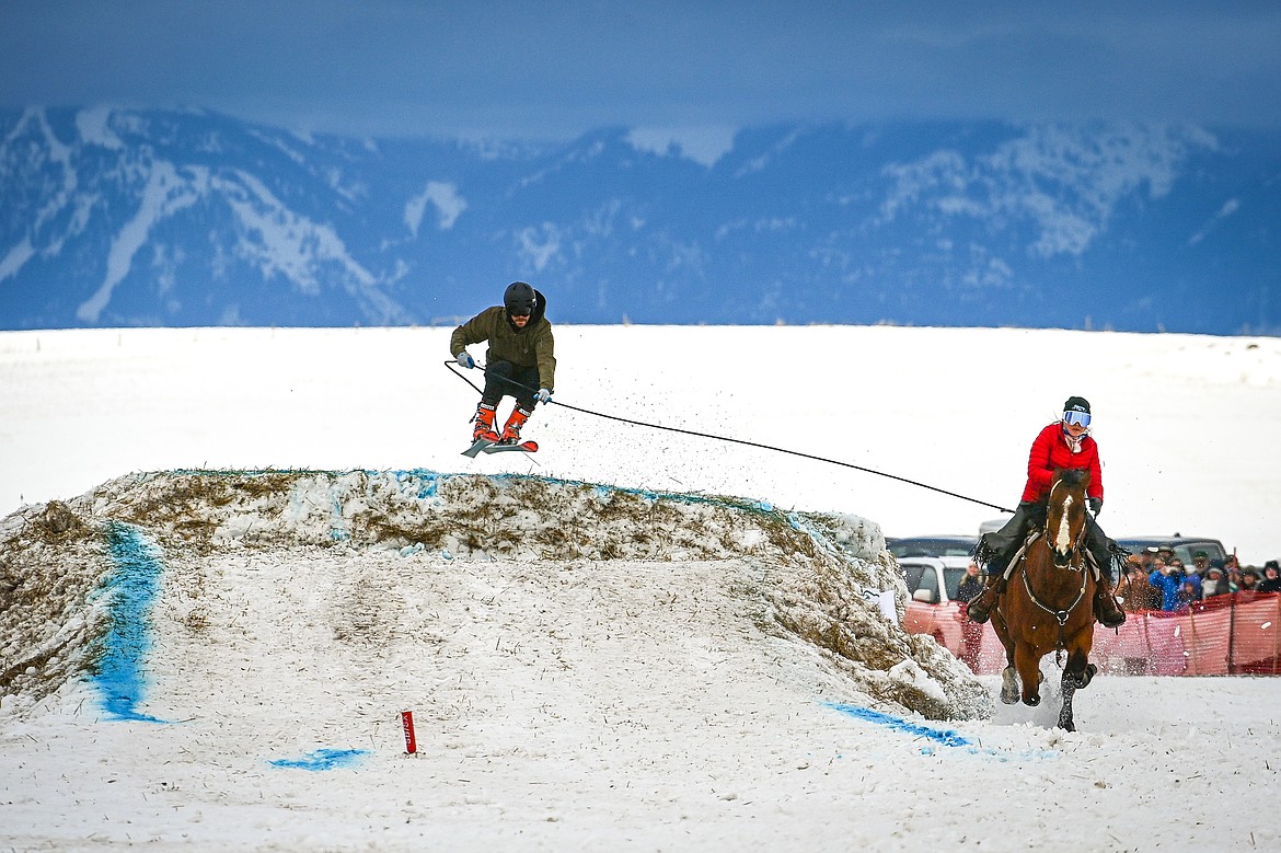 A horseback rider pulls a skier over a jump at Whitefish Skijoring on West Springcreek Road on Saturday, Feb. 22. (Casey Kreider/Daily Inter Lake)