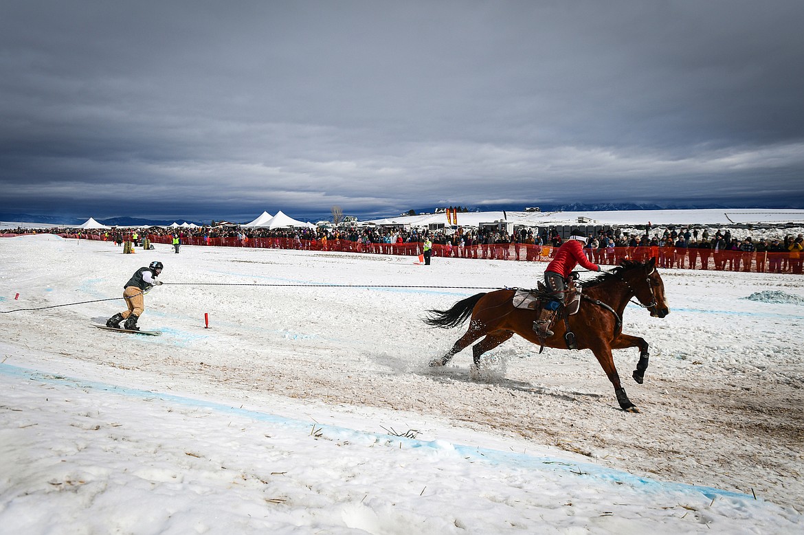 A horseback rider pulls a snowboarder through the course at Whitefish Skijoring on West Springcreek Road on Saturday, Feb. 22. (Casey Kreider/Daily Inter Lake)