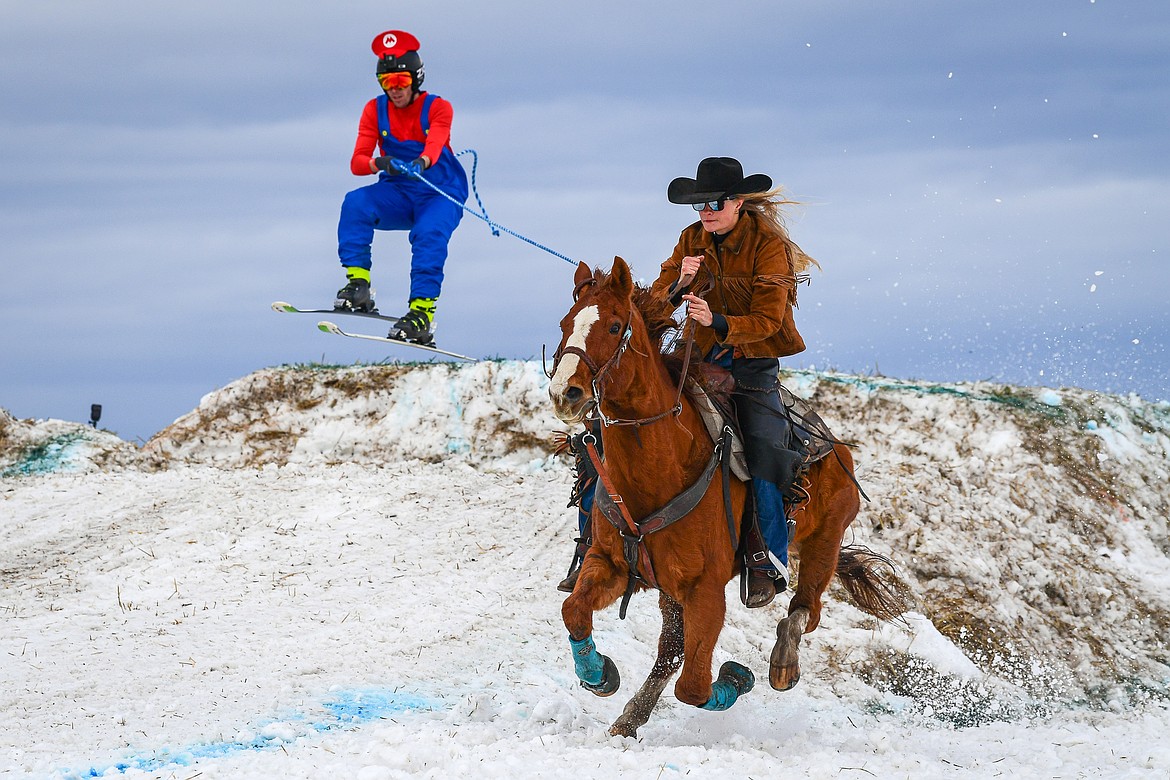 A horseback rider pulls a skier over a jump at Whitefish Skijoring on West Springcreek Road on Saturday, Feb. 22. (Casey Kreider/Daily Inter Lake)