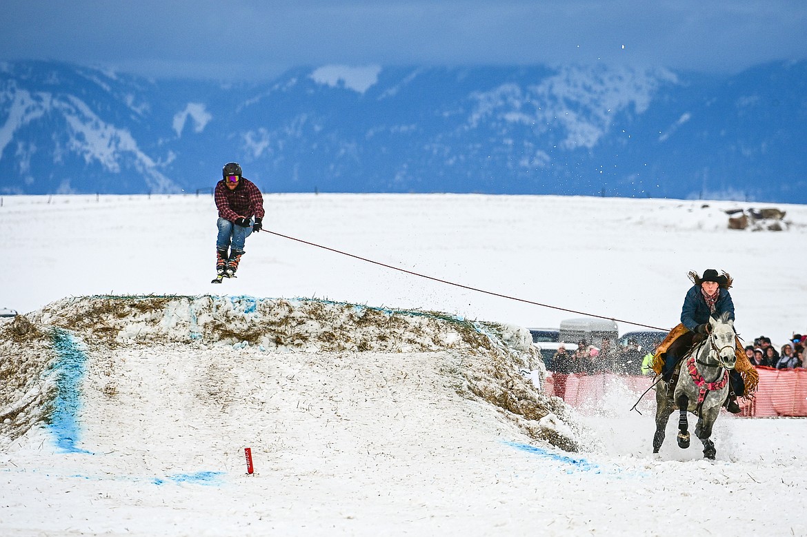 A horseback rider pulls a skier over a jump at Whitefish Skijoring on West Springcreek Road on Saturday, Feb. 22. (Casey Kreider/Daily Inter Lake)