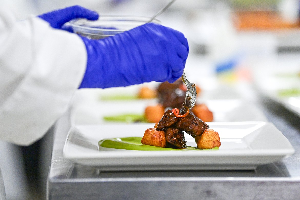 Max Malcomson adds a spoonful of truffles and mushrooms to garnish a Sirloin Beef Steak Tips entree at a Chef's Table dinner series held by Flathead Valley Community College's Culinary Institue of Montana on Friday, Feb. 21. (Casey Kreider/Daily Inter Lake)