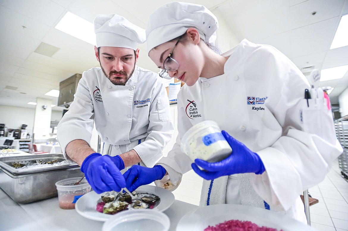 Conor Sears and Kaylee Bishop add shallot mignonette and chive creme fresh to a dish of oysters on the half shell during an amuse-bouche at a Chef's Table dinner series held by Flathead Valley Community College's Culinary Institue of Montana on Friday, Feb. 21. (Casey Kreider/Daily Inter Lake)