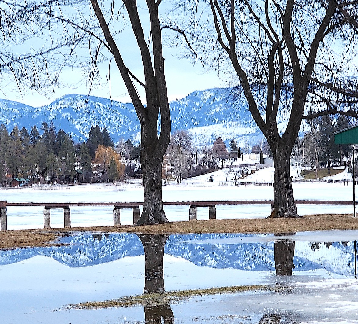Last week's snow melted and left a pool showing a perfectly smooth reflection of the Mission Mountains. The pool is on the lawn at Boettcher Park in Polson, but it's drying up fast. (Berl Tiskus/Leader)