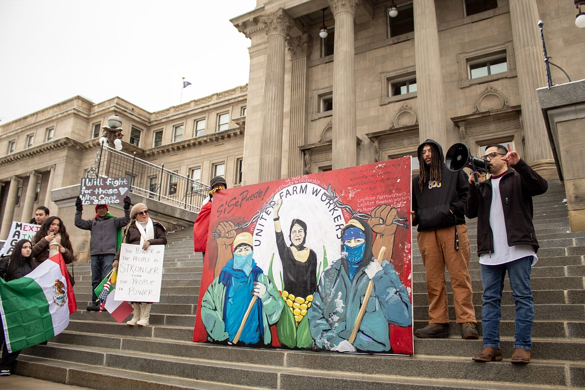 Eddie Melendrez, a Chicano artist, speaks in a megaphone while showcasing his mural representing the United Farmworkers of America, a labor union that advocates for farmworker rights. Melendrez, and nearly 100 others, protested President Donald Trump’s immigration policies in front of the Idaho State Capitol in Boise on February 7, 2025. (Mia Maldonado / Idaho Capital Sun)