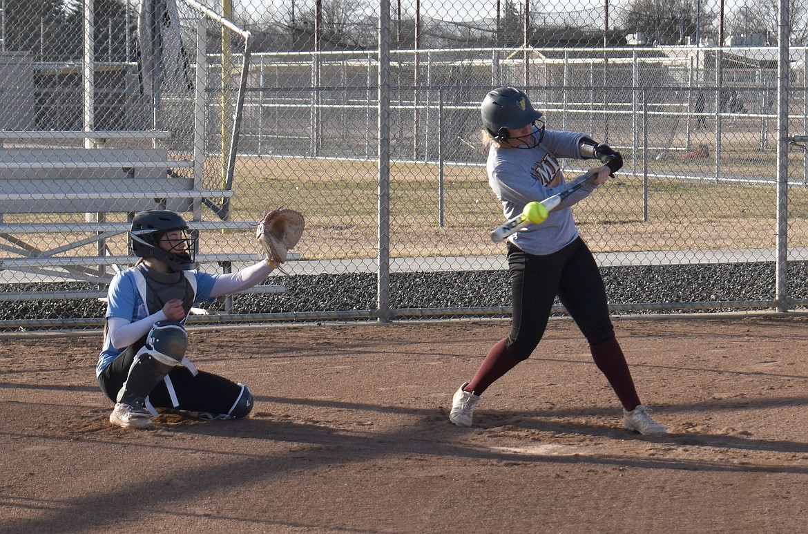 Eryn Eckenberg, right, makes contact with the ball while catcher Hayden Morris holds up her glove in vain at a Moses Lake High School softball practice Friday.