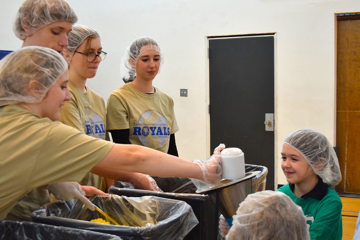 First grader Evelyn Regan works alongside a group of eighth graders as part of North Idaho Christian School's efforts to package over 10,000 meals on Thursday for the school's Feed the Need campaign.