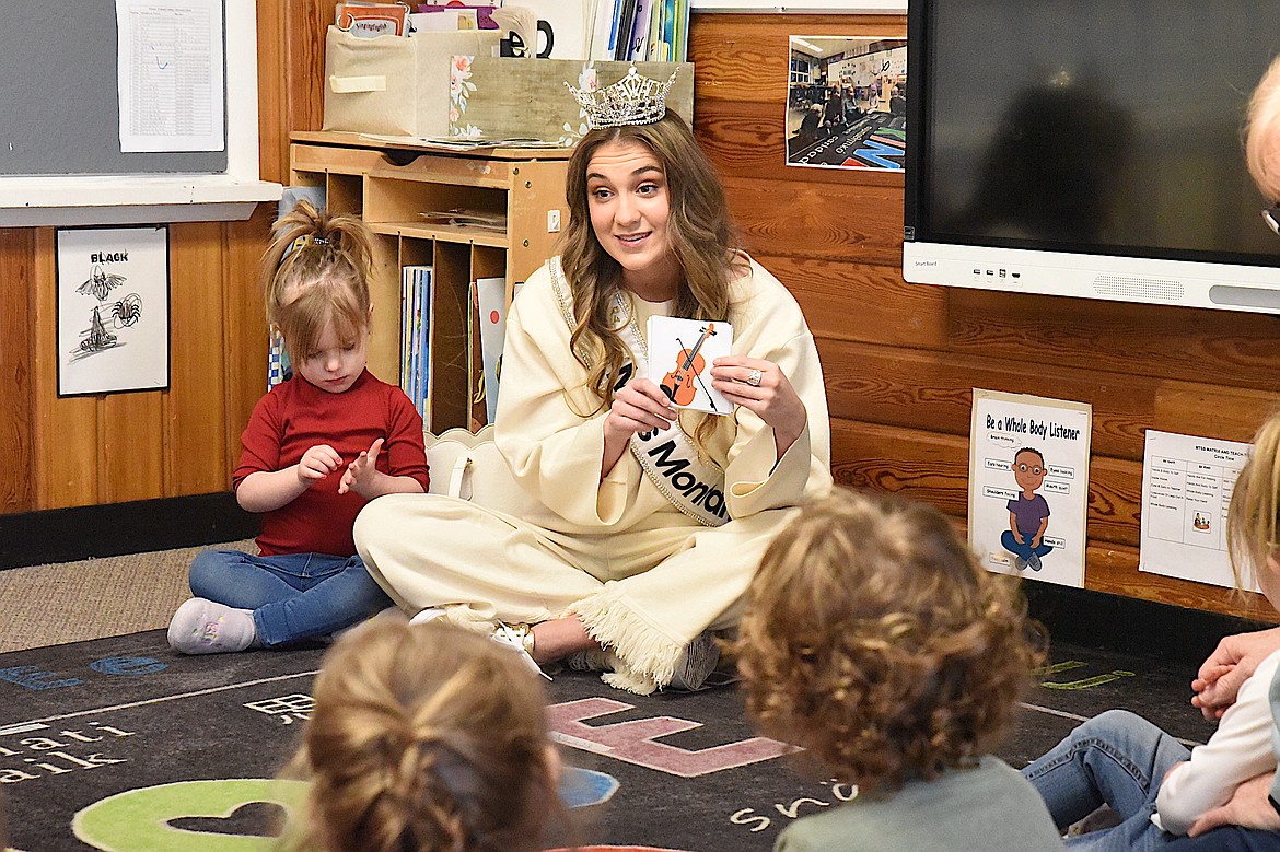 Miss Montana Kaylee Wolfensberger shows a picture of a violin while Emma Reed listens during her presentation Tuesday, March 18, 2025, at the Kootenai Valley Head Start in Libby. (Scott Shindledecker/The Western News)
