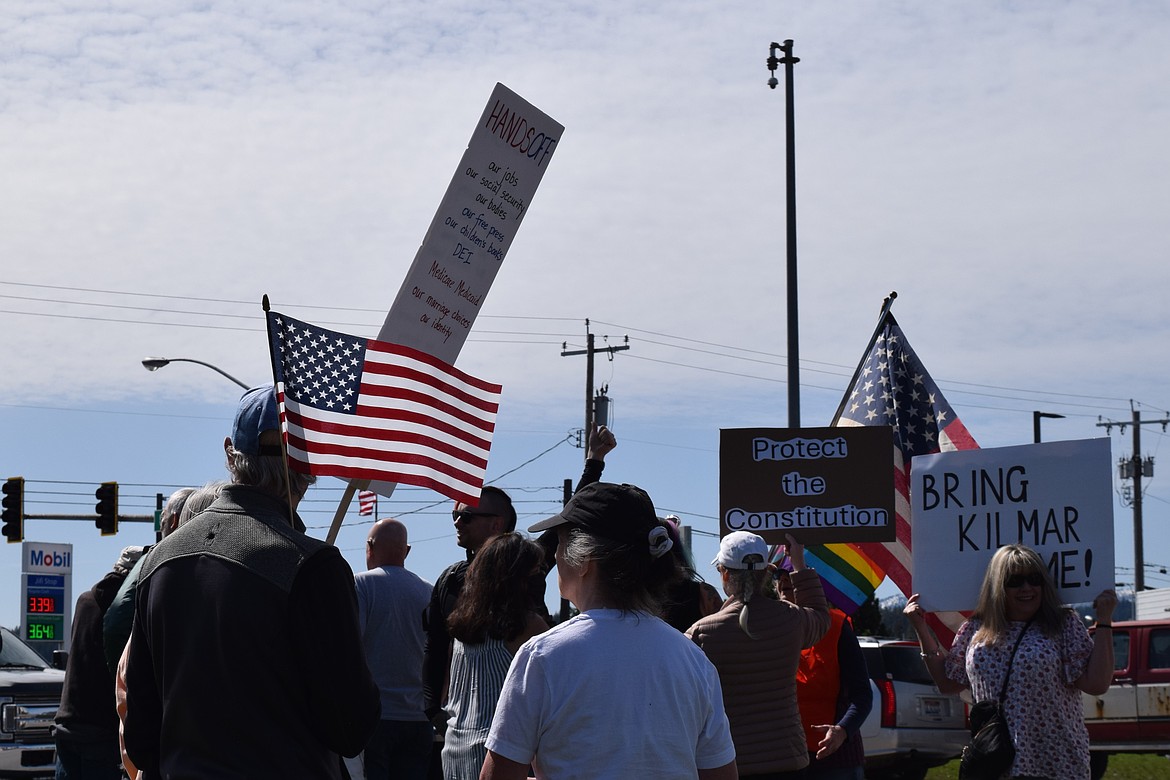 A man holds an American flag as he observes protestors along U.S. 95 in Coeur d'Alene on Saturday.