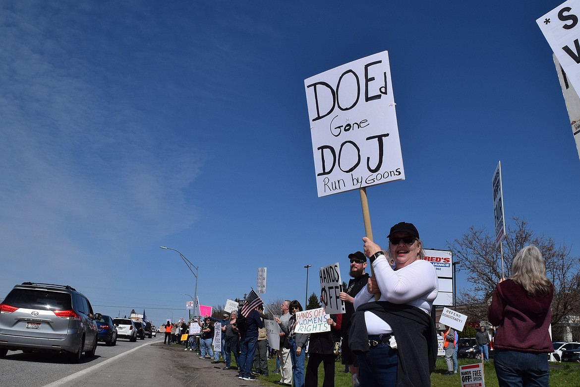 A woman holds a sign protesting cuts to the Department of Education on Saturday.