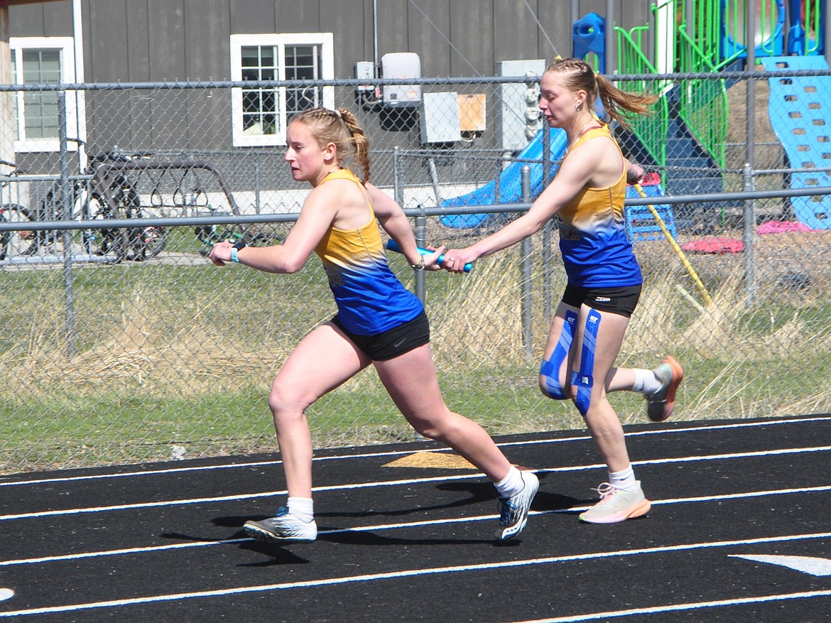 Thompson Falls relay team members Peighton Kenney and Evy Edwards pass the baton during the Bigfork Invitational track and field meet this past weekend.  (Photo by Sarah Naegeli)