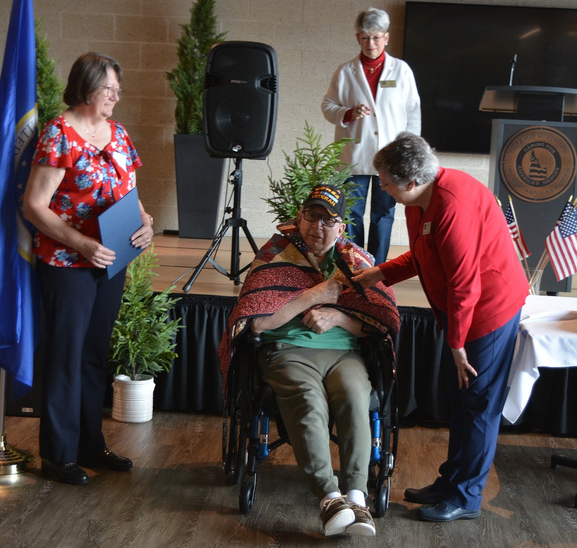 Susan McMinimy and Giannine O’Connor present Duaine Johnson with a quilt for his Air Force service Monday at the Idaho State Veterans Home Post Falls. Johnson took off his Korea veteran hat to thank the quilters.