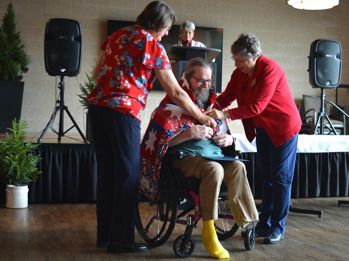 Susan McMinimy and Giannine O’Connor drape a quilt of valor over Kenneth Siirila's shoulders to commemorate his Army service Monday at the Idaho State Veterans Home Post Falls.