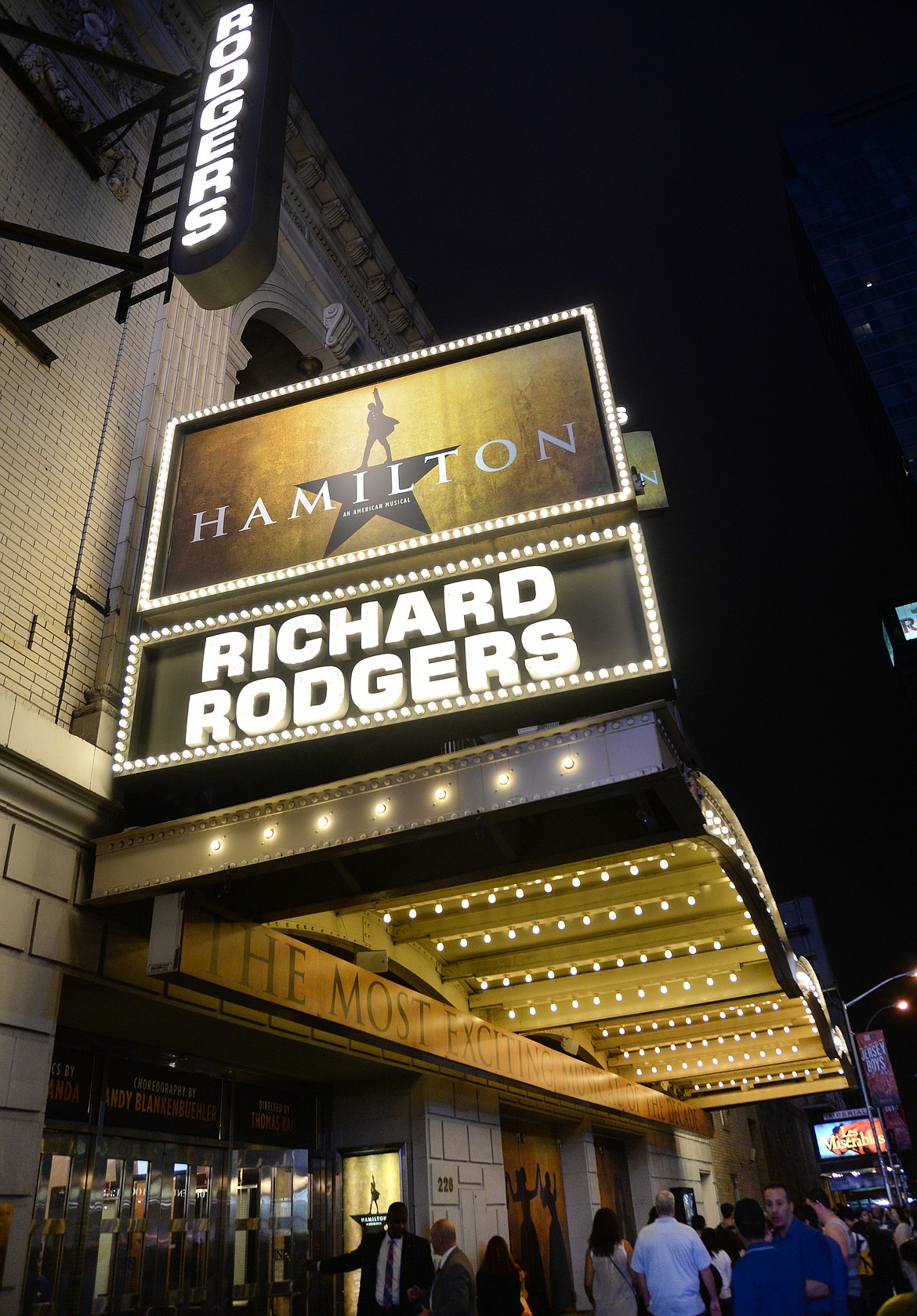 People walk near the "Hamilton" marquee at the Richard Rogers Theatre on Saturday, July 9, 2016, in New York.