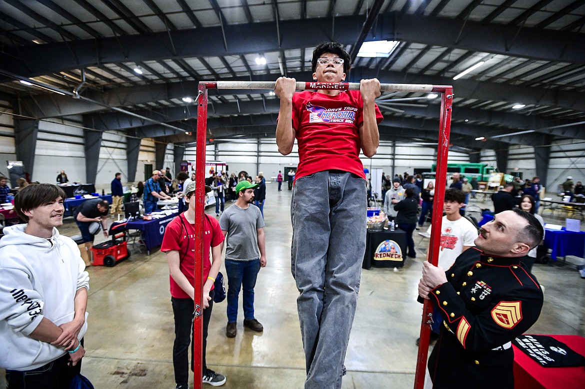 Wesley Adams, from Hot Springs High School, does chin-ups for a T-shirt with Marine Corps Staff Sgt. Ryan C. Steward at the Marine Corps Recruiting Station at the Northwest Montana Job and Opportunity Fair on Thursday, April 17. (Casey Kreider/Daily Inter Lake)