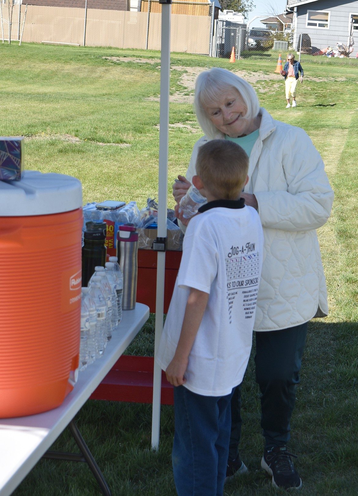 Crestview Christian School volunteer Azure Goltz gives first-grader Ben Spencer a drink of water at the school’s Jog-a-Thon Friday morning.